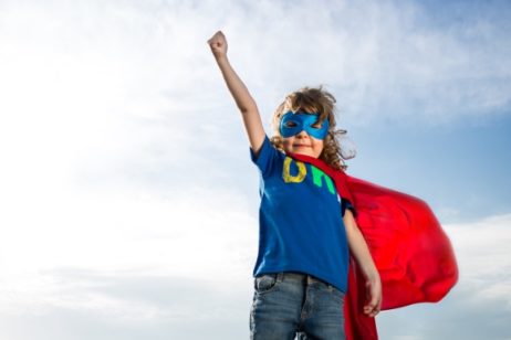 kid in red cape and blue mask with raised fist