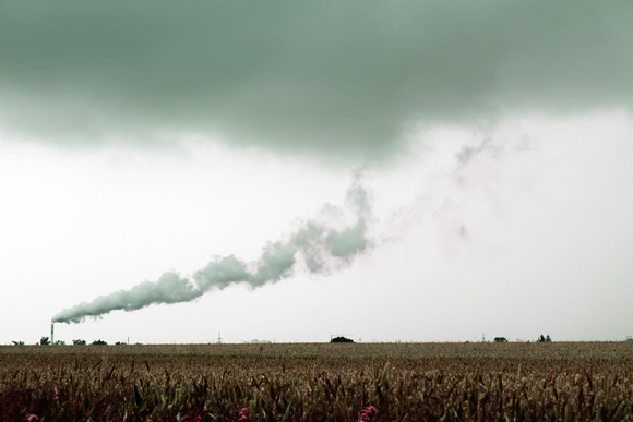 Pollution coming from a smokestack and hovering over a field