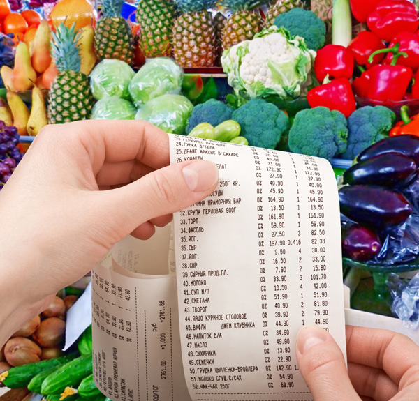 Hands holding cash register receipt in front of produce section