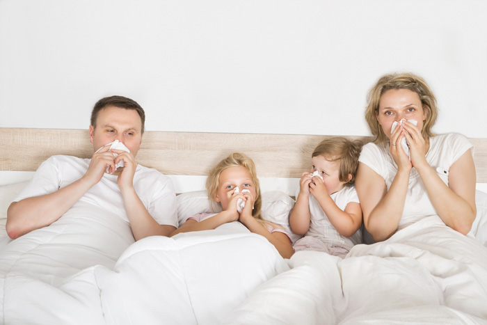 family_blowing_noses_bed