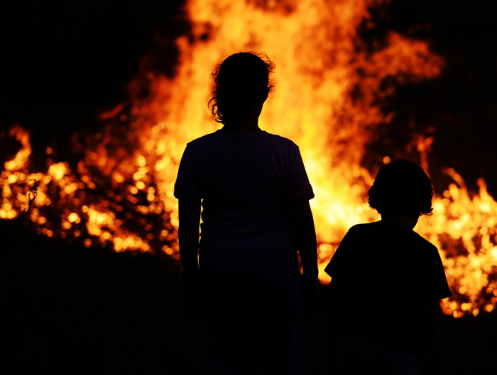 Silhouetttes of children watching a wildfire from afar
