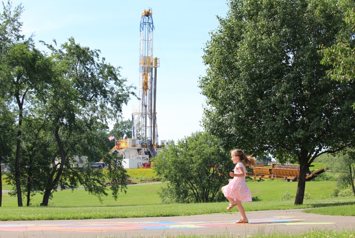 Little girl playing near oil drilling rig
