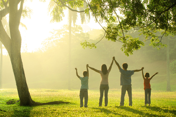 Family with hands raised in victory watching a sunrise