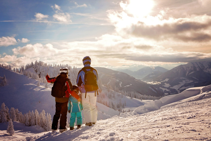 Family in ski clothing looking out over snowy slopes