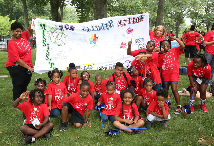 Mississippi parents and kids hold up banner at the play-in for climate action