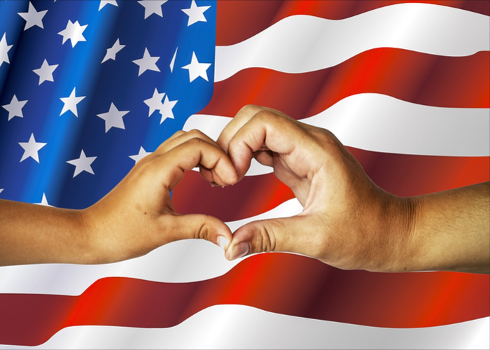 Hands making a heart in front of a flag