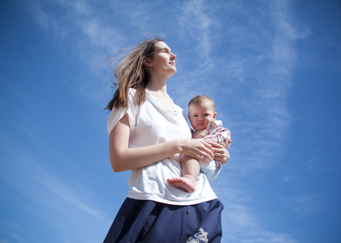 Mother carrying child under blue sky