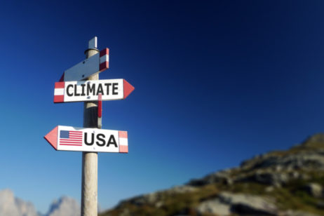 signpost with climate pointing in one direction and the U.S. pointing in another