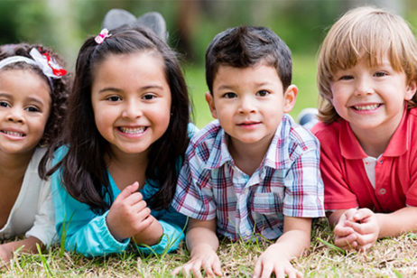 smiling kids lined up laying on the ground