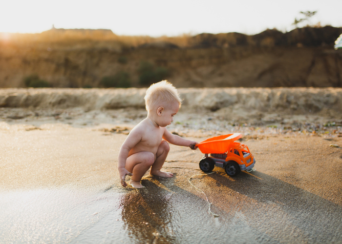 toddler enjoys the natural world with his truck at the shore