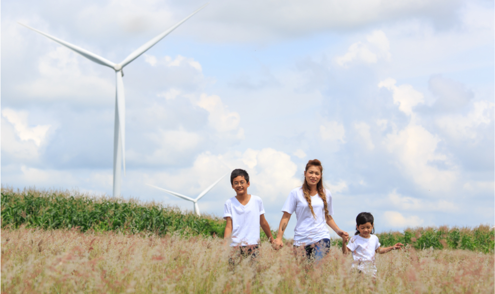 a family plays near wind turbines, which provide clean energy