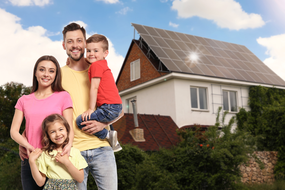 Family standing in front of house with solar panels, a source of clean energy