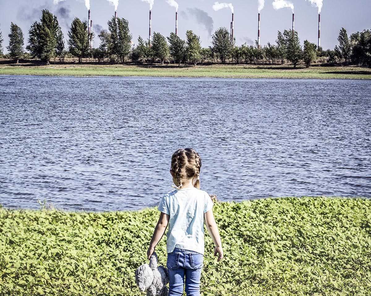 child across the water from power plants
