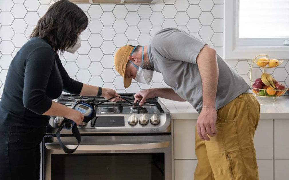 two adults checking gas stoves for leaks