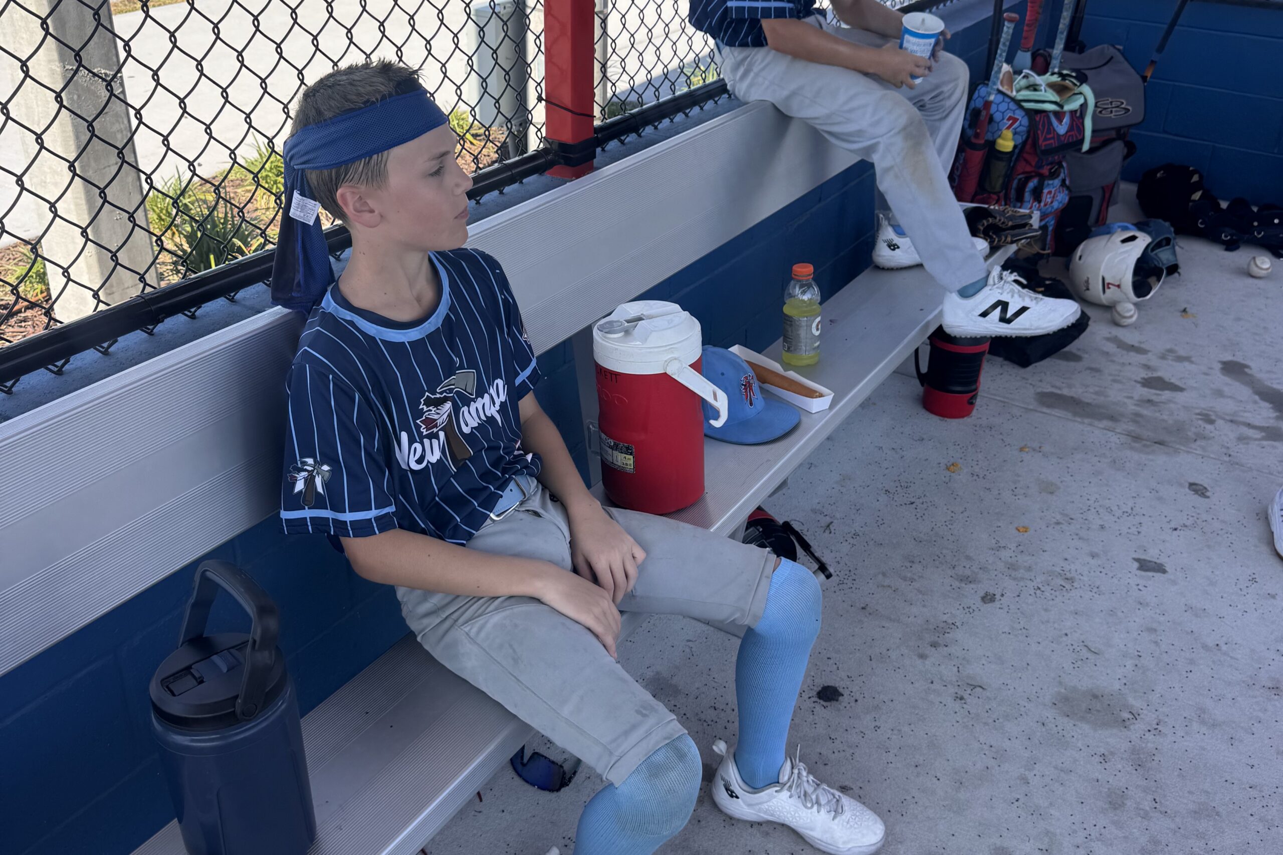 young baseball player cooling down in the dugout