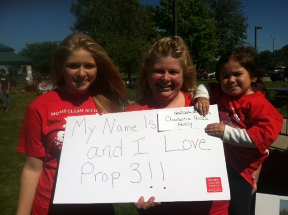 Mom and children holding up sign, supporting Prop 3 in Michigan