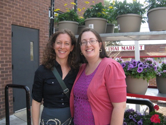 Two women in standing outside of a safeway store with potted plants in the background