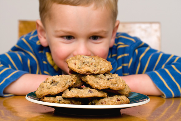 A young boy staring at a plate of cookies