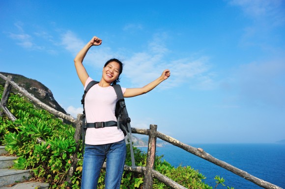 A woman with raised arms as she pauses hiking up stairs