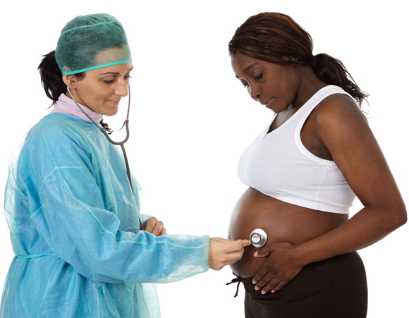 Doctor listening with stethescope to pregnant woman's belly