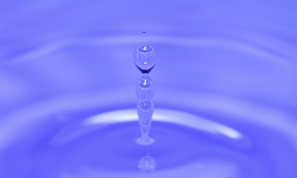 Photo of a water drop falling into a pool of water