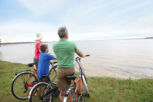 Family riding bikes overlooking a lake