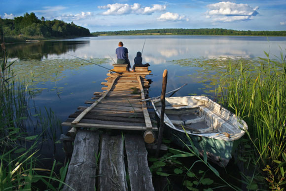 Father and son fishing on a dock in a lake
