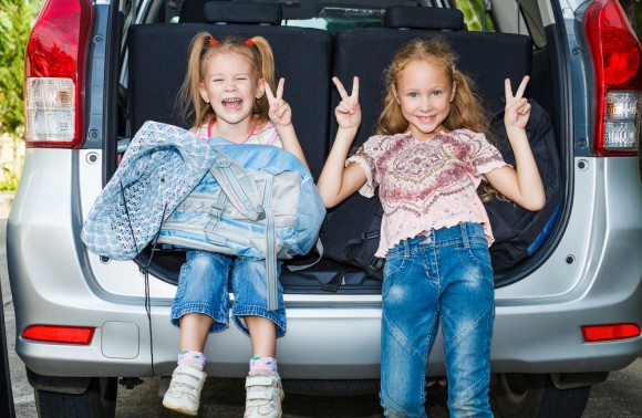 Two girls sitting in the back of a SUV trunk 