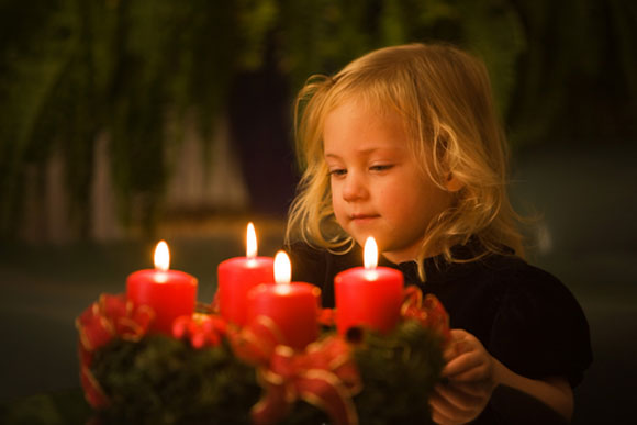 Little girl standing near holiday candles
