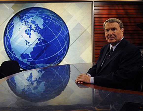 Jim Lehrer sitting at a news desk