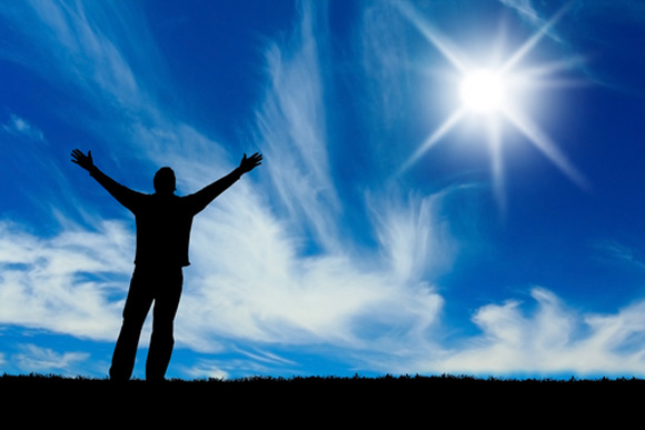 Man holding arms up in front of blue sky
