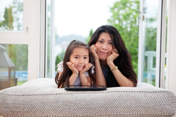 Mother and daughter leaning on an ottoman in front of open patio doors