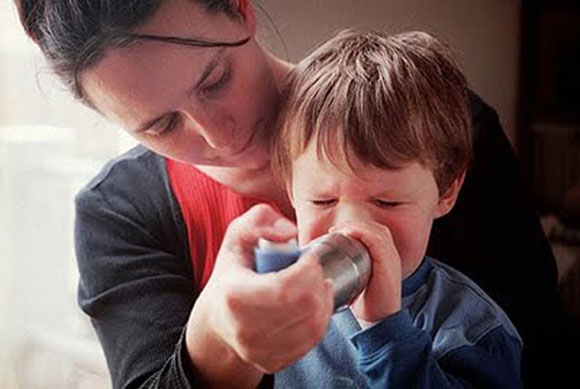 Mother helps young son with asthma inhaler