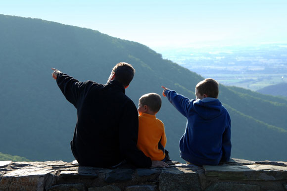 Da and two sons pointing out over a hazy mountain view