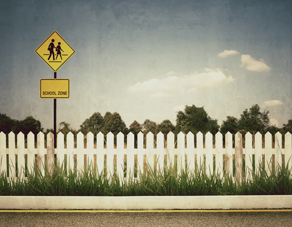 school zone sign behind a white picket fence