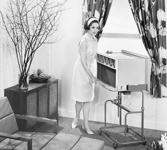 A 1950s housewife moves an air conditioning unit 