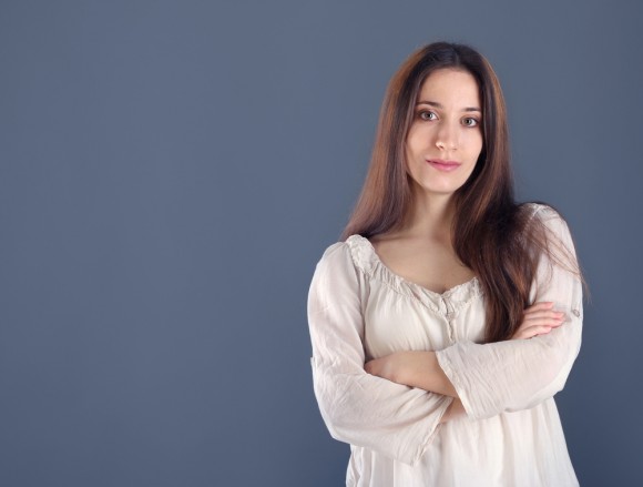 Woman in white blouse standing in front of plain blue background
