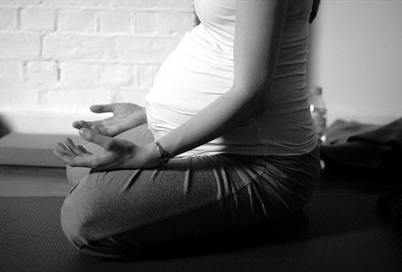 Pregnant woman sitting in yoga position practicing yoga breathing